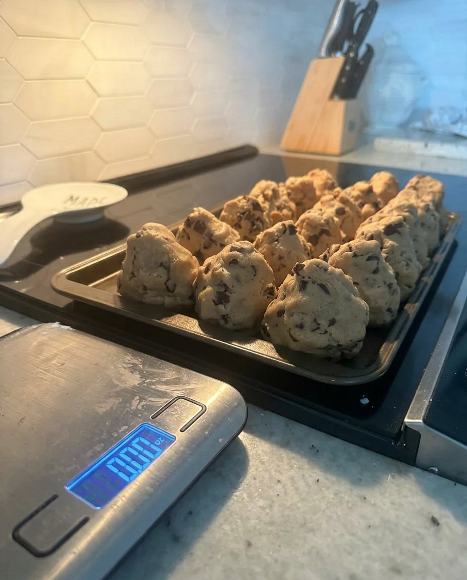 Scooping cookie dough onto a parchment lined baking sheet.