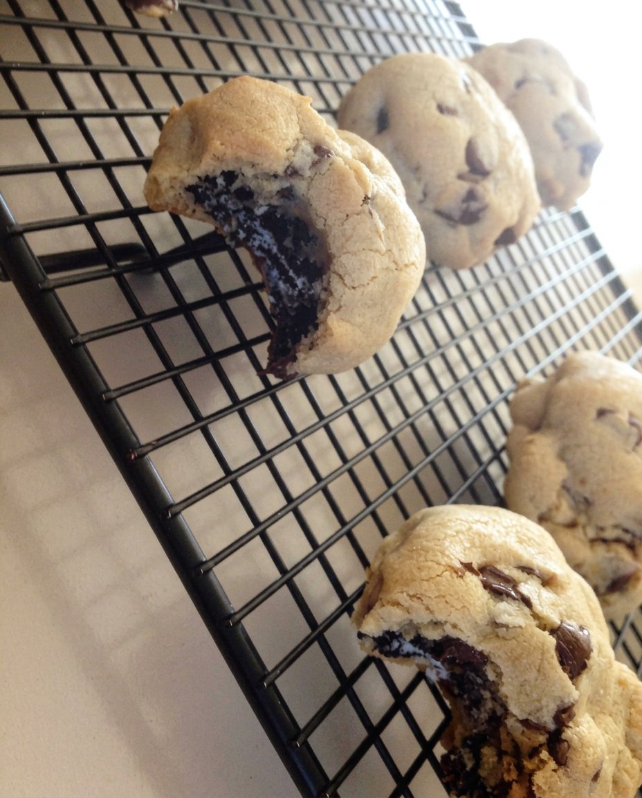 Large cookies stacked next to a glass of milk and a vintage ceramic cookie jar.