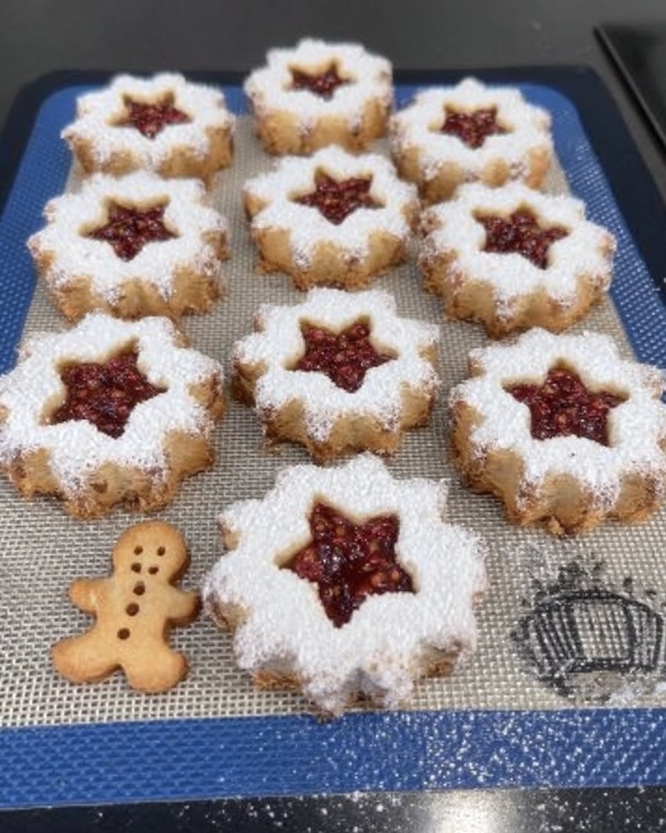 A white platter filled with finished raspberry linzer cookies
