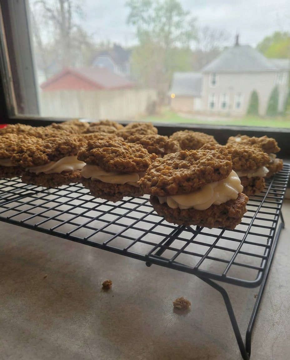 A glass of milk next to a plate of oatmeal cream pie sandwiches