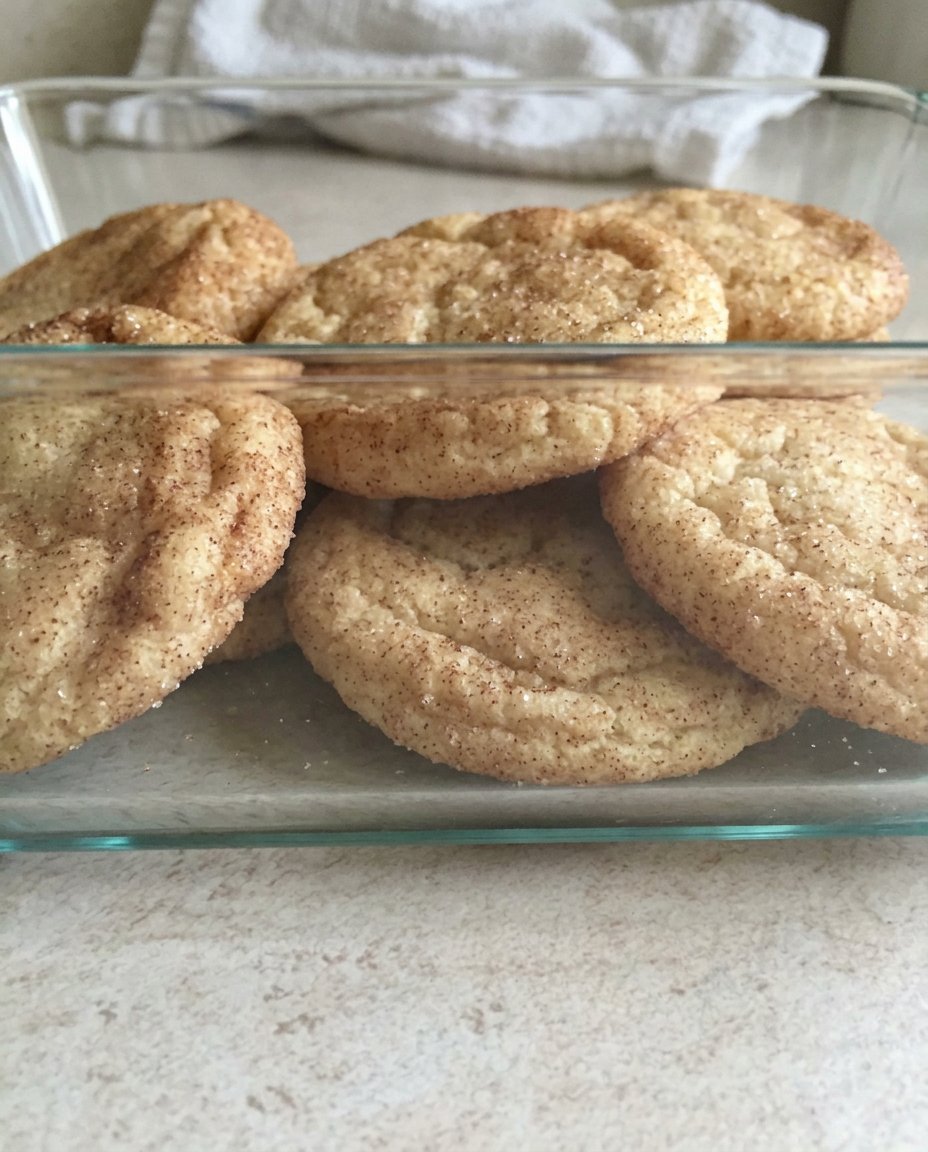 A stack of soft chewy gluten free snickerdoodles inside a glass cookie jar