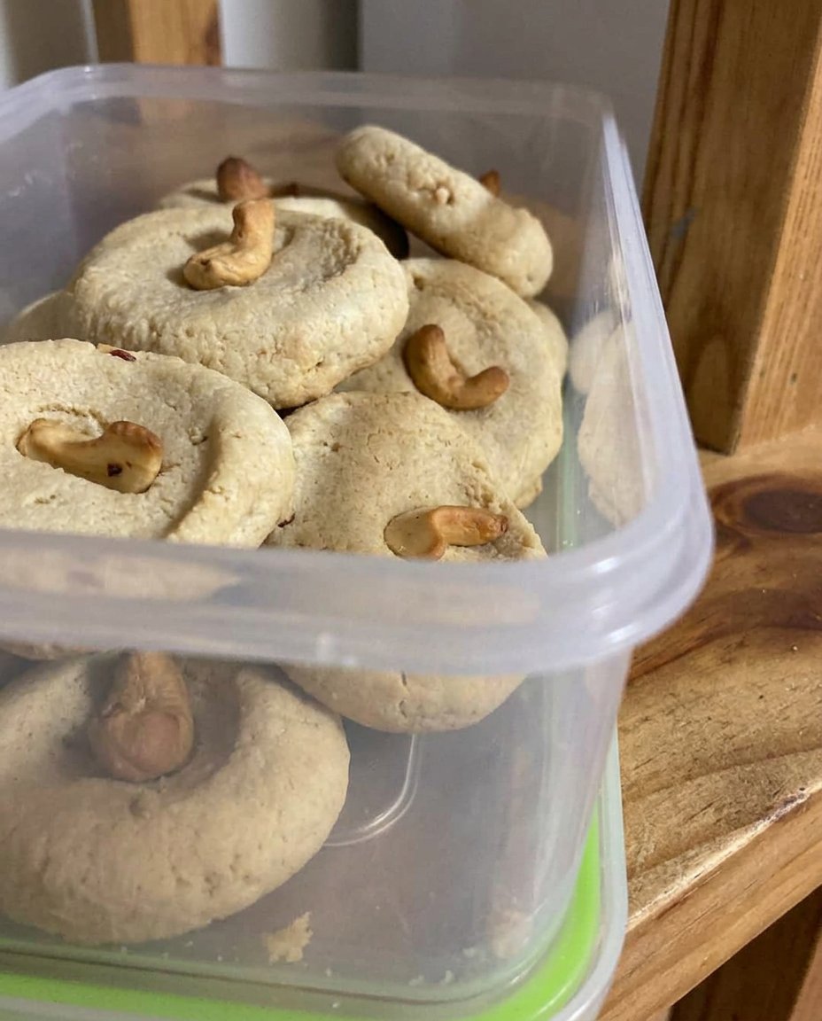 A pile of soft cashew shortbread cookies with browned butter frosting in a vintage jar.