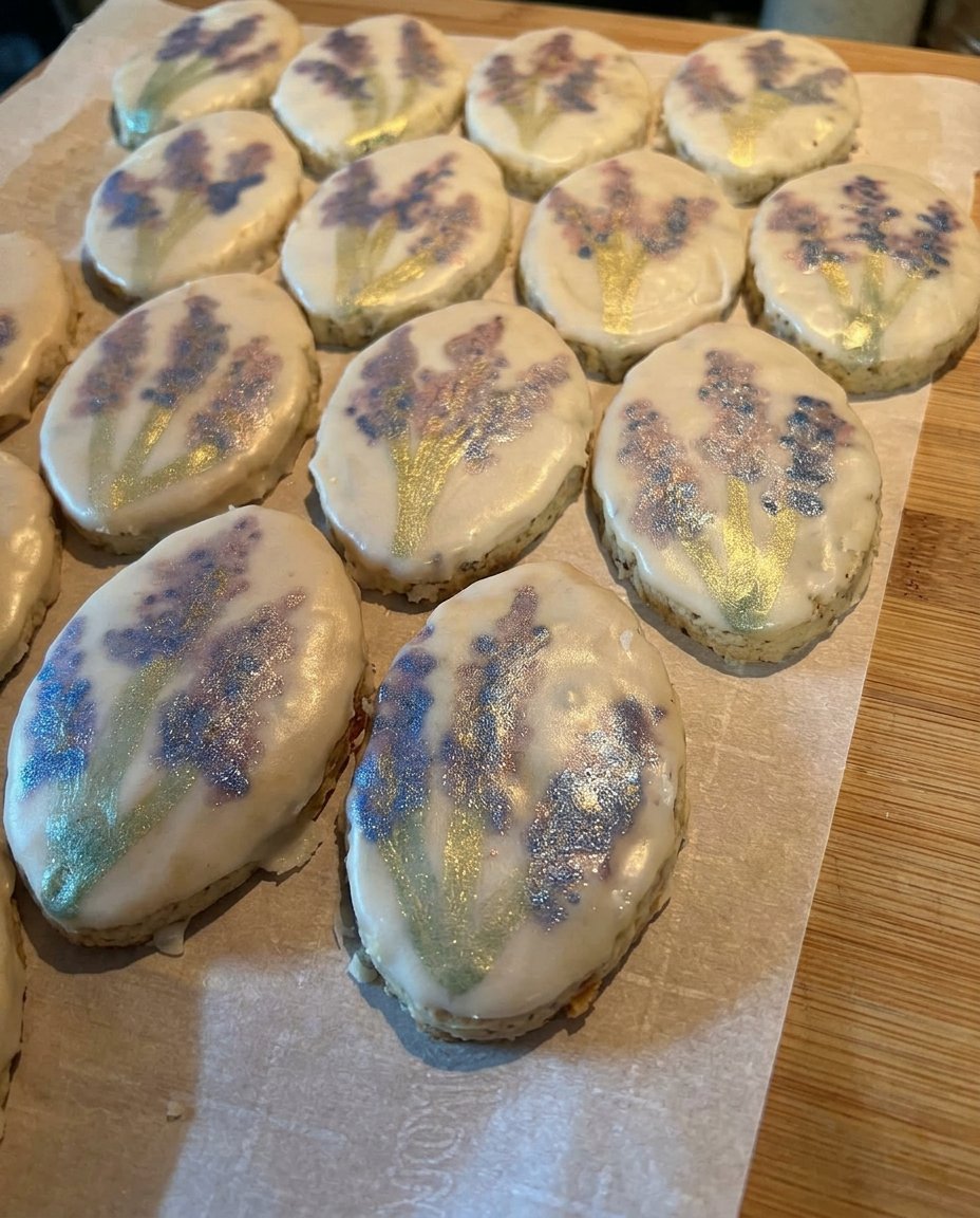 Old-fashioned lavender shortbread cookies stacked next to a vintage glass cookie jar